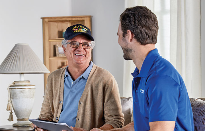 A patient holding a clipboard talks with a CenterWell Home Health clinician